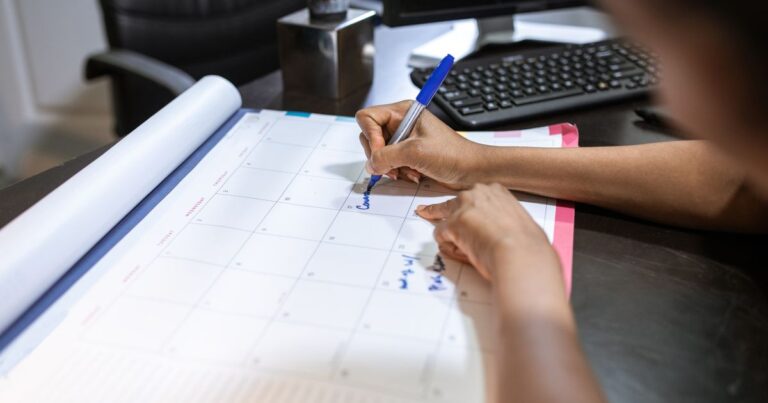 Close up of a person marking dates on a desk calendar, illustrating Gap Cover waiting periods in South Africa
