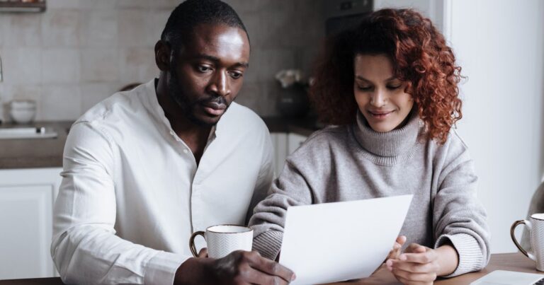 Couple reviewing paperwork together at a kitchen table at home